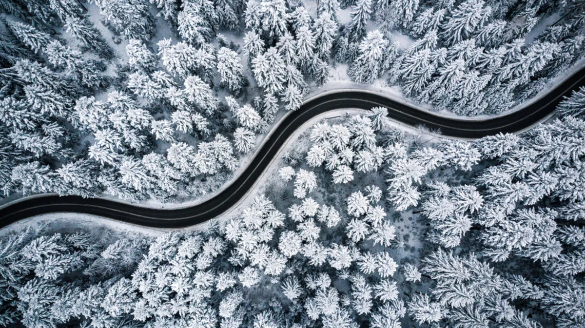 A drone photo of a snowy winter road in the forest | Skylum Blog