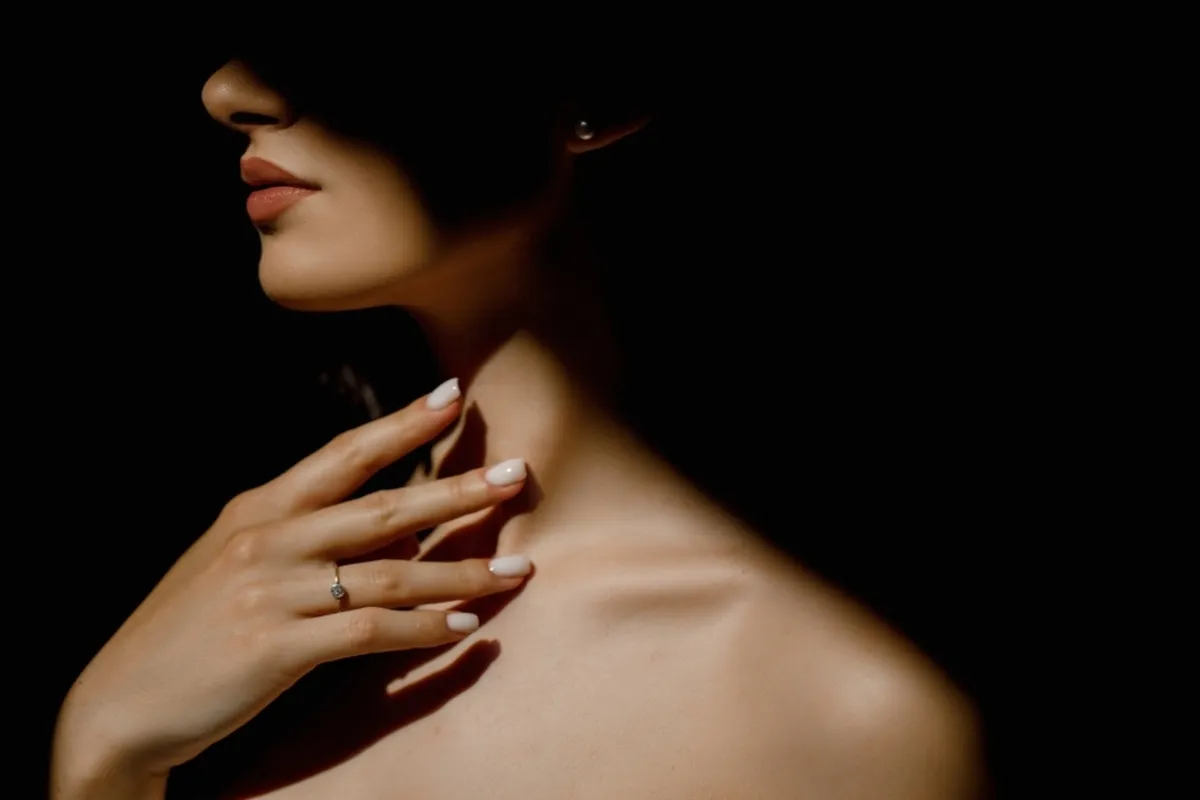 Girl in the shadows with her hand on her collarbone | Skylum Blog