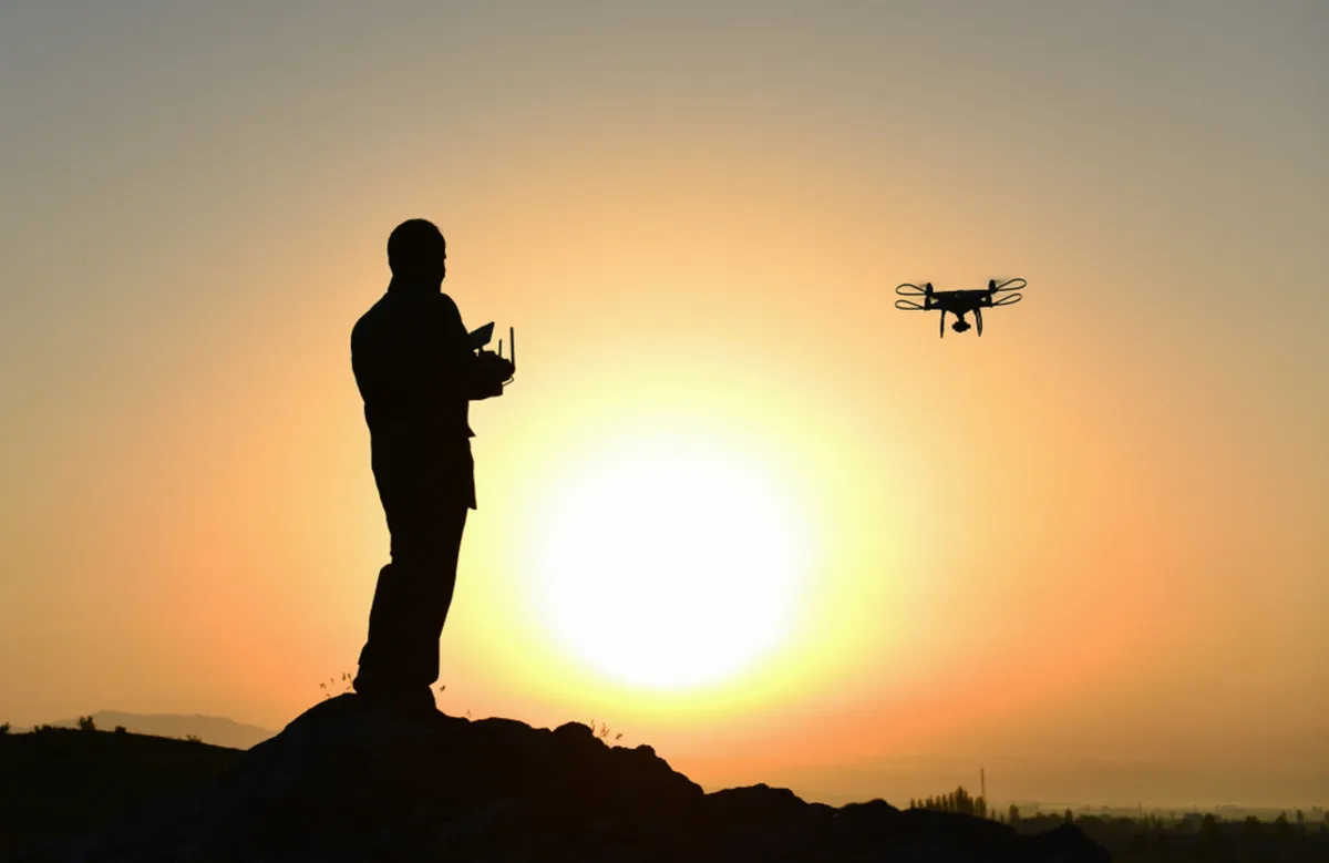 A man launches a photography drone during golden hour | Skylum Blog
