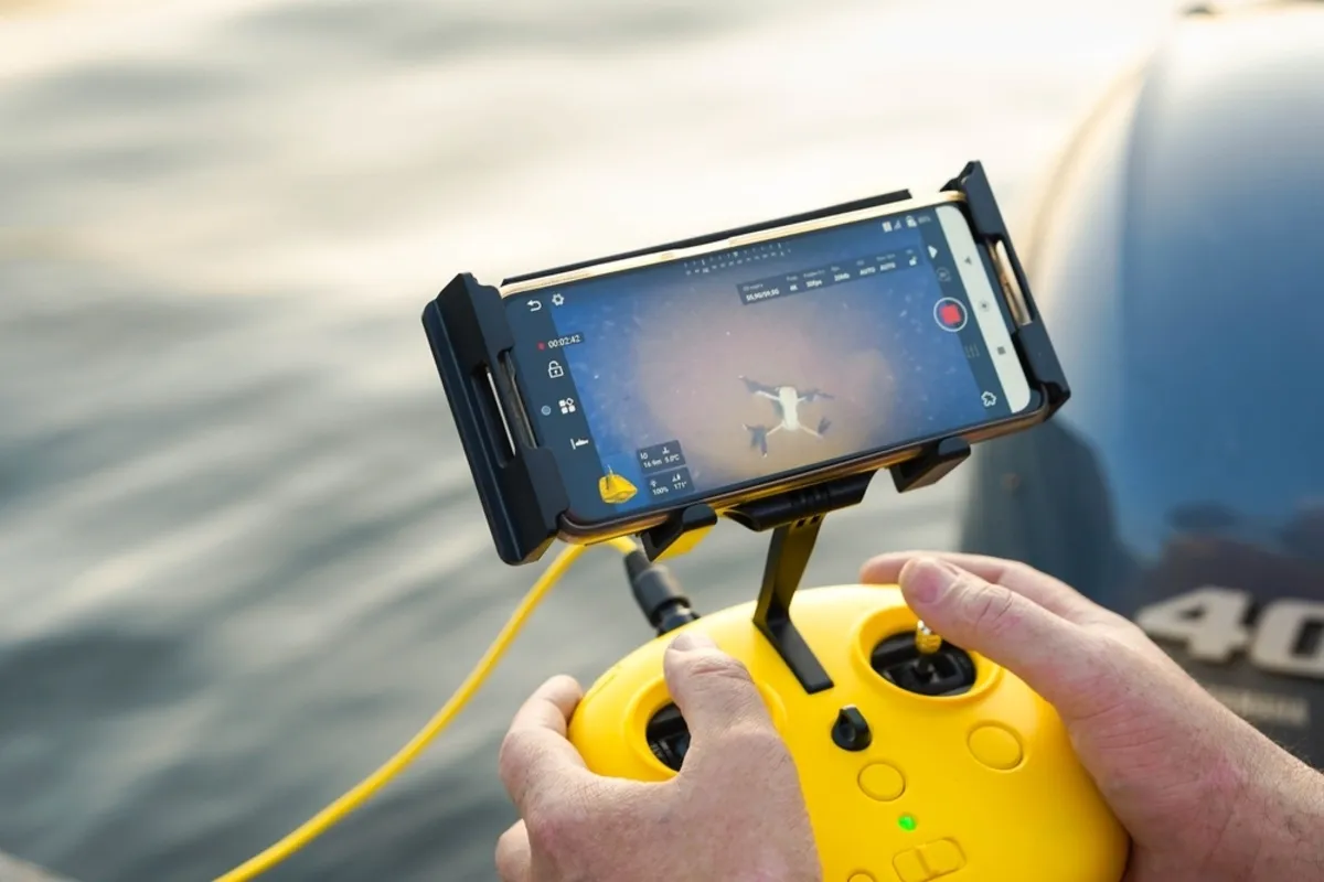 A man holds the remote control for an underwater drone | Skylum Blog