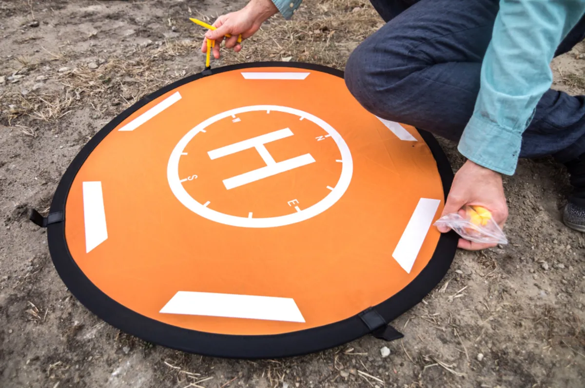 A man sets up a landing pad for drones | Skylum Blog