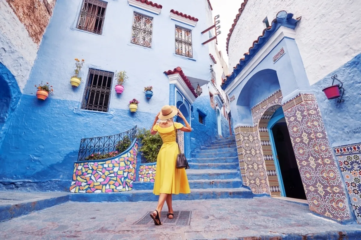 A girl in a yellow dress in front of blue buildings | Skylum Blog
