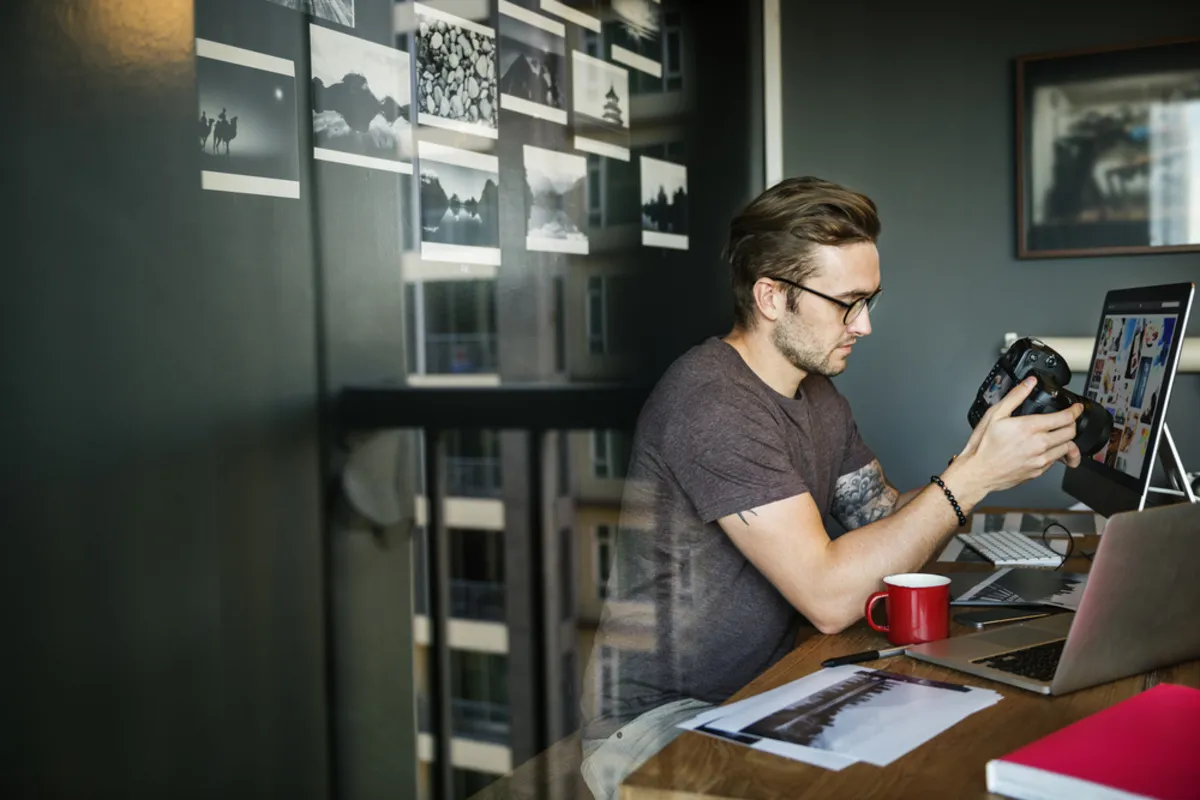 A photographer in a studio looks at a photo on a camera | Skylum Blog