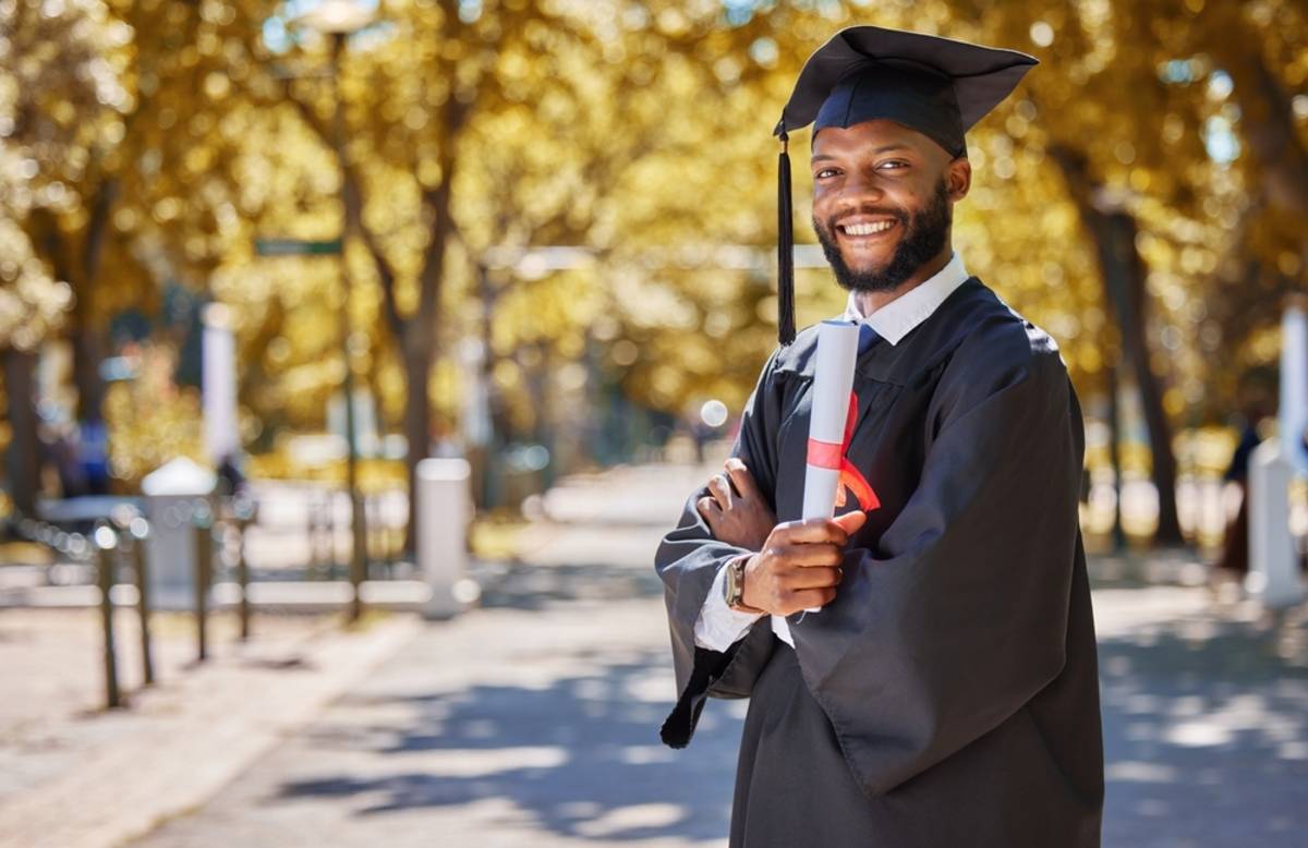 Graduate standing on a tree-lined street | Skylum Blog

