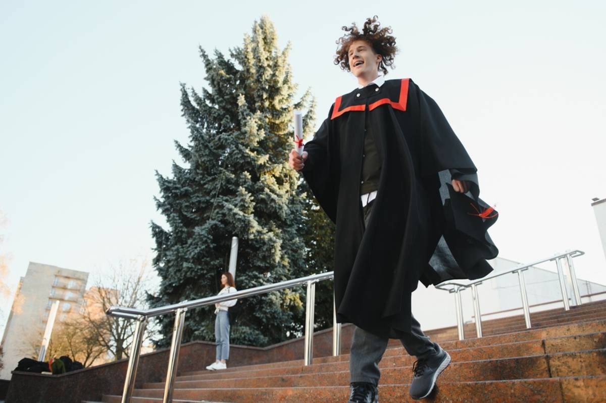 Graduate walking outdoors in a cap and gown | Skylum Blog