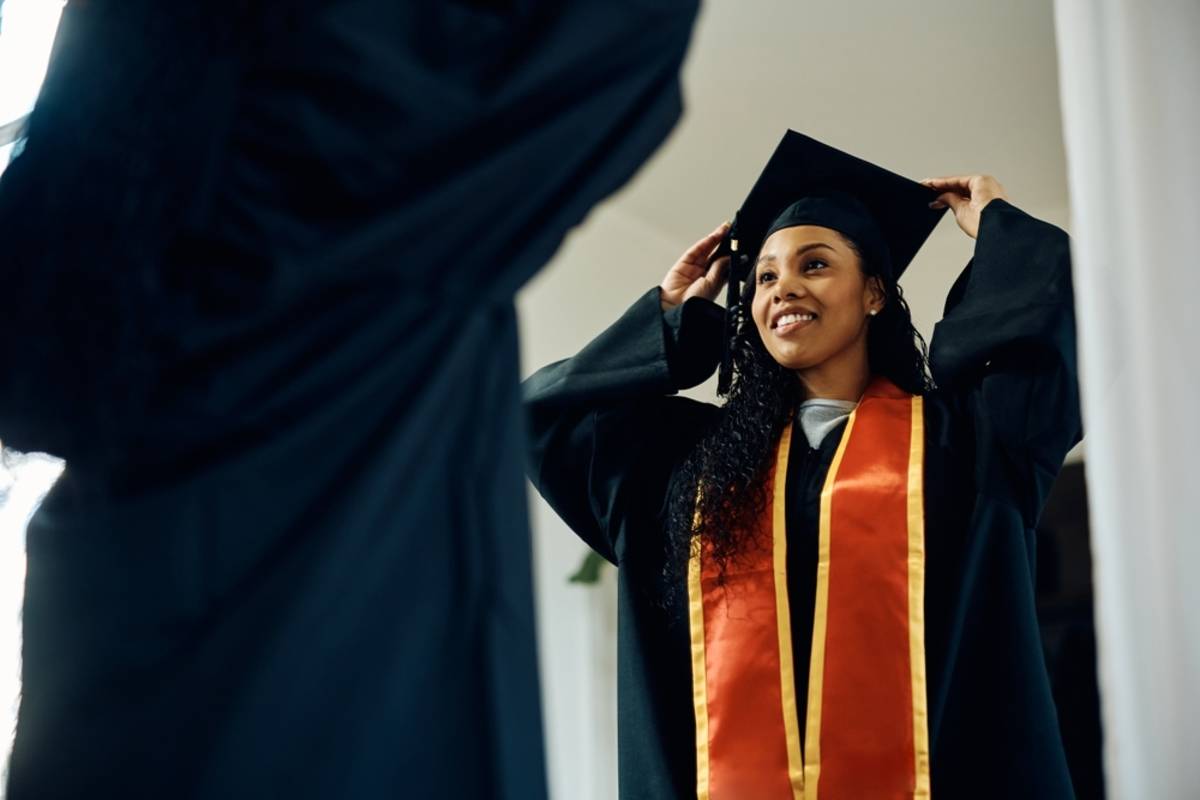 Graduate adjusting a cap in a reflective surface | Skylum Blog

