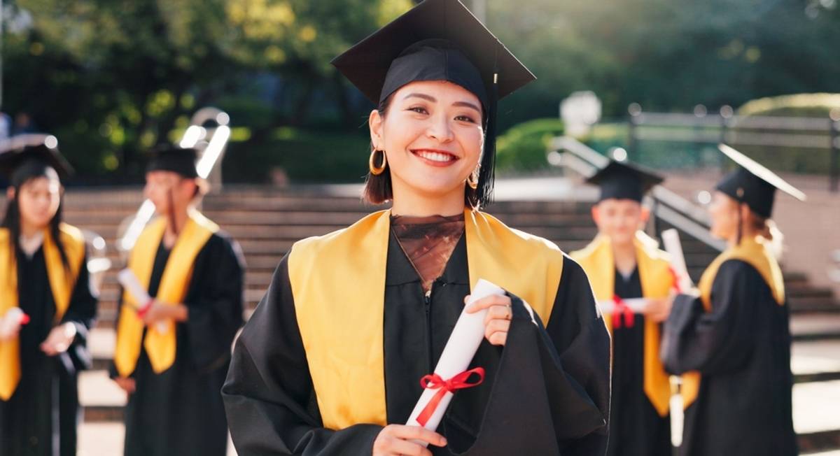 Graduate holding a diploma with classmates behind | Skylum Blog