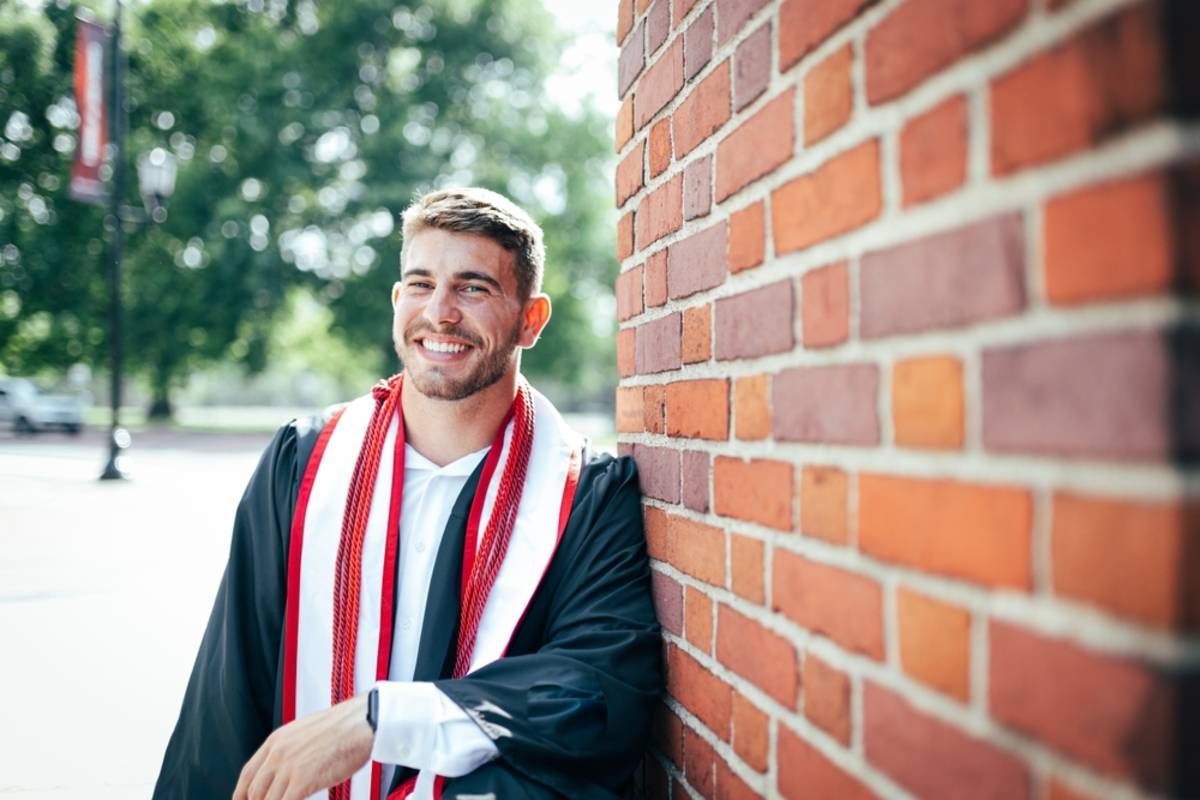 Graduate leaning against a brick wall | Skylum Blog

