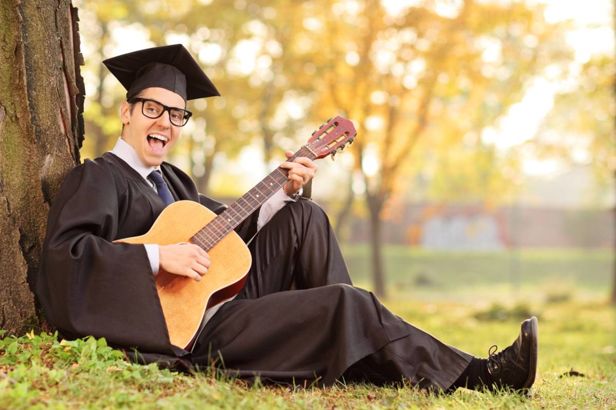 Graduate sitting outdoors with a guitar | Skylum Blog


