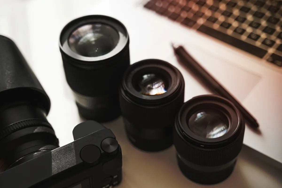 Lenses on the table near the camera and laptop | Skylum Blog