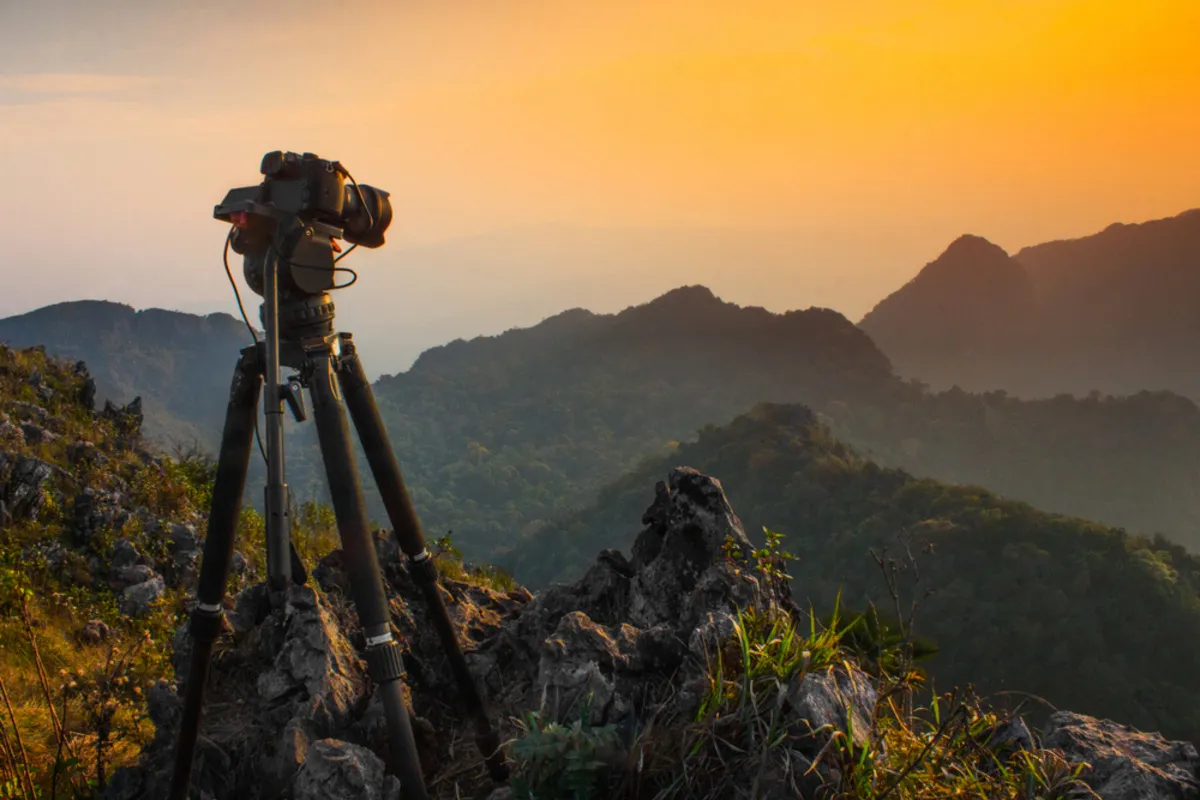 Camera on a tripod in front of the sunset | Skylum Blog