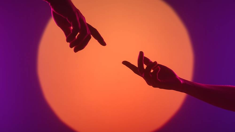 Two hands reaching out against a glowing sun | Skylum Blog

