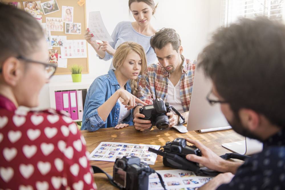 Group of photographers reviewing camera shots together | Skylum Blog