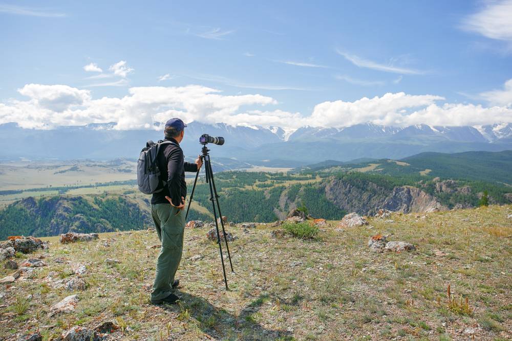 Photographer taking photos of landscape with tripod | Skylum Blog