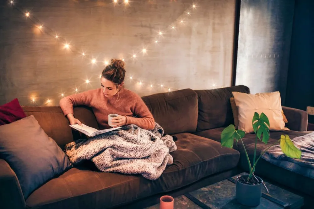 Girl Reading a Book on the Sofa in a Cozy Living Room | Skylum Blog
