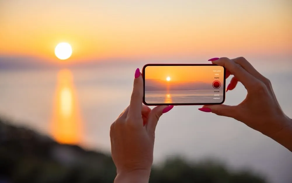 Girl Taking a Picture of the Sun on Her Phone | Skylum Blog
