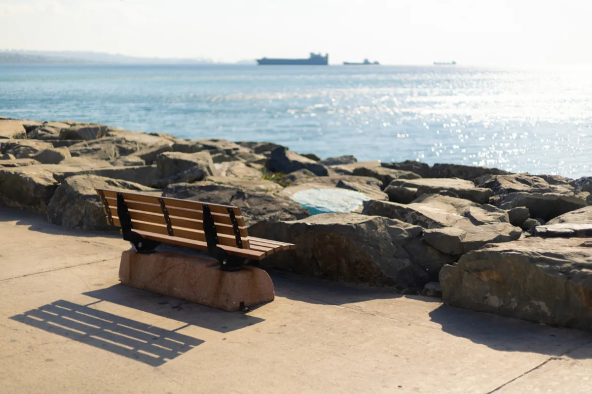 Photo of a bench with the sea in the background | Skylum Blog
