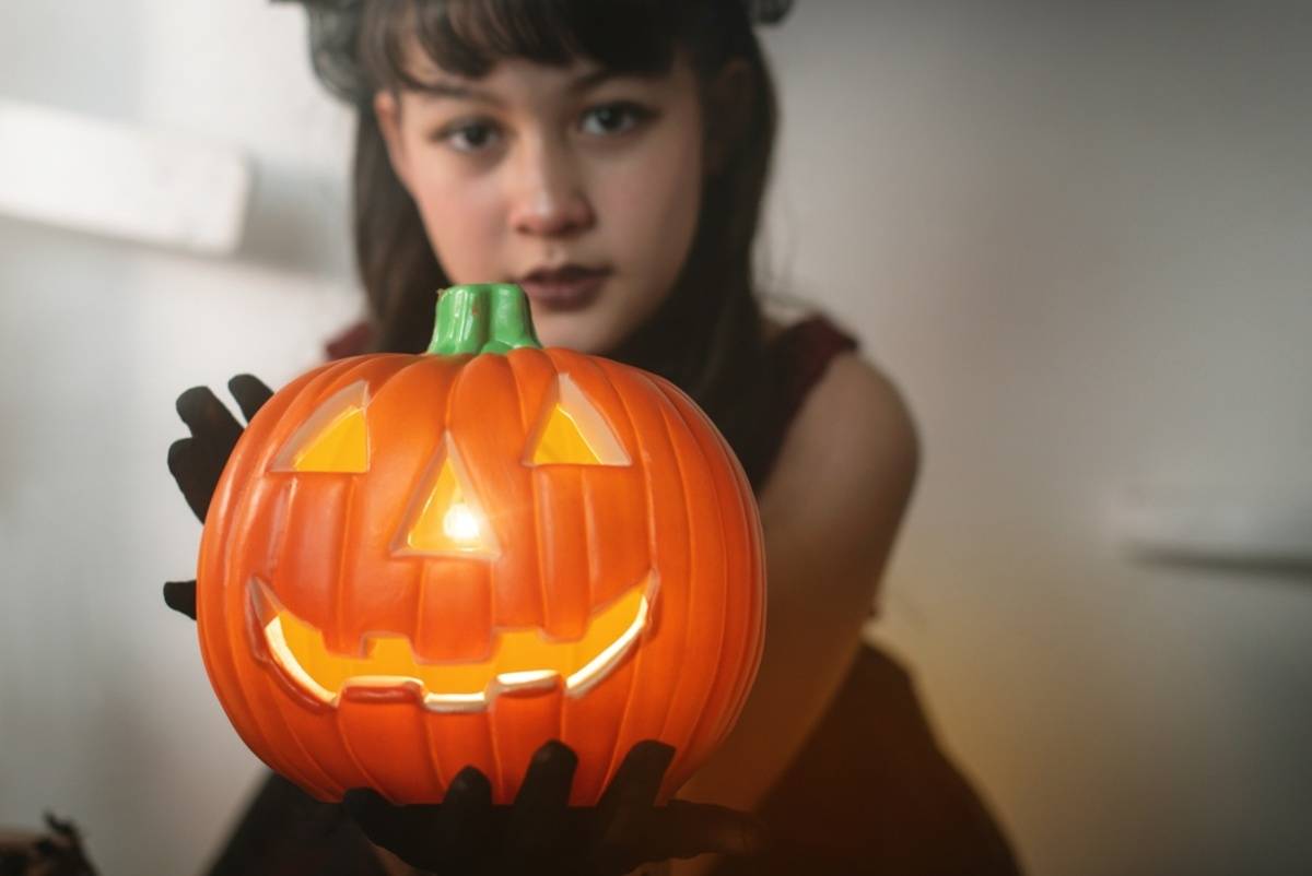 Child holding a glowing carved pumpkin | Skylum Blog

