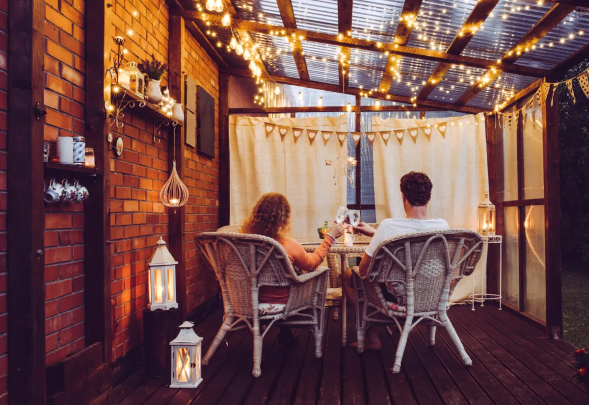 A guy and a girl on a veranda with garlands in autumn | Skylum Blog