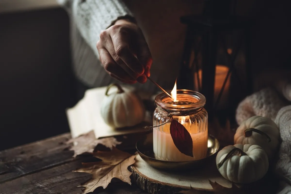 A girl in a sweater lights a candle in autumn | Skylum Blog