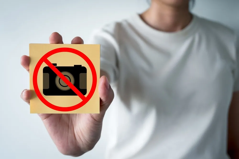A girl holds a picture of a crossed-out camera in her hands | Skylum Blog