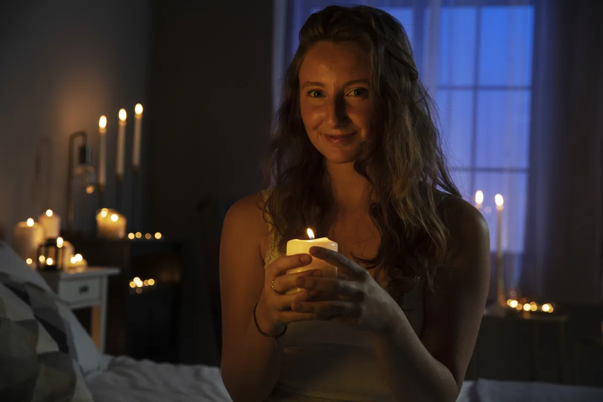 A girl in a room with candles holds a candle in her hands | Skylum Blog