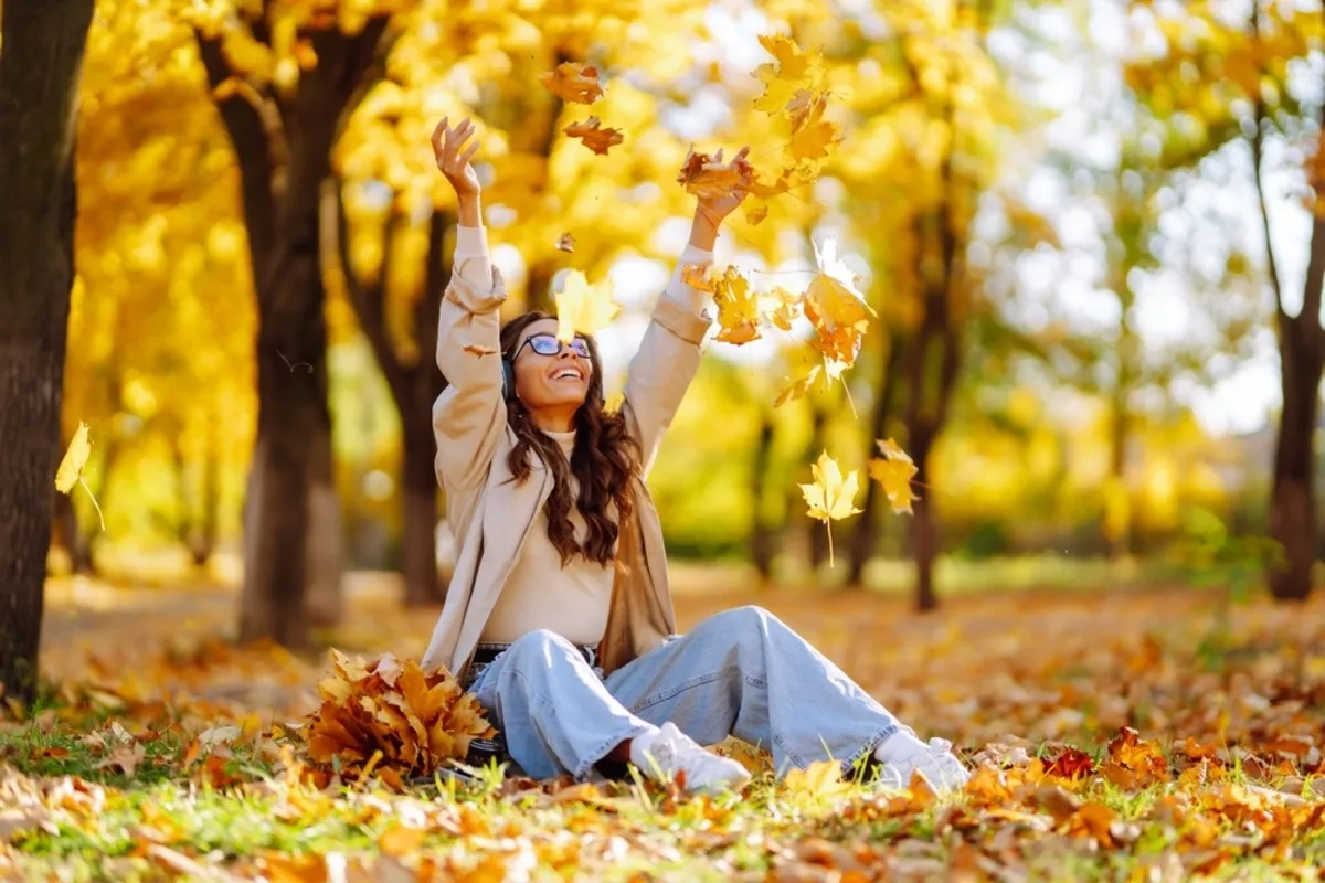 A girl sits and throws autumn leaves | Skylum Blog