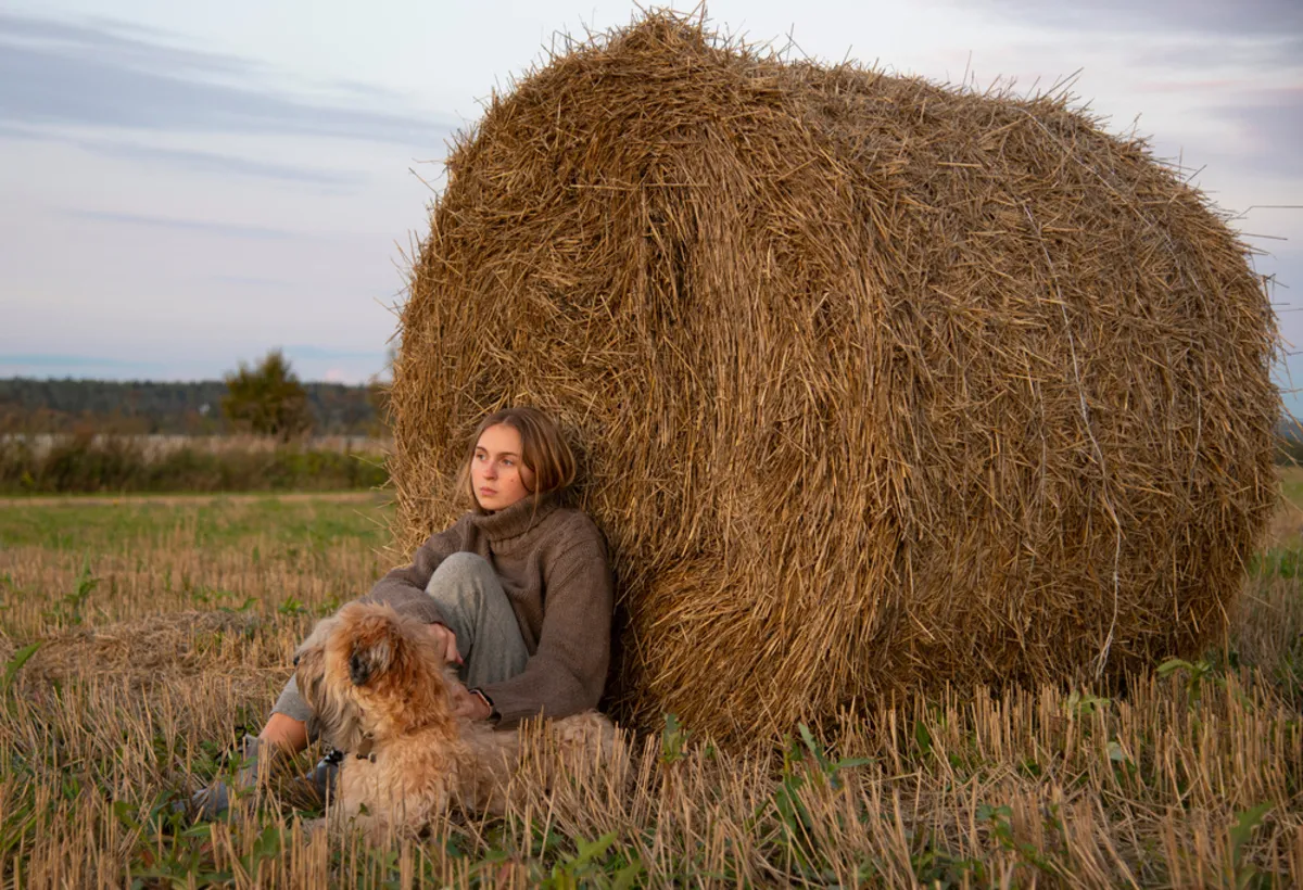 A girl with a dog near a bale of hay in autumn | Skylum Blog
