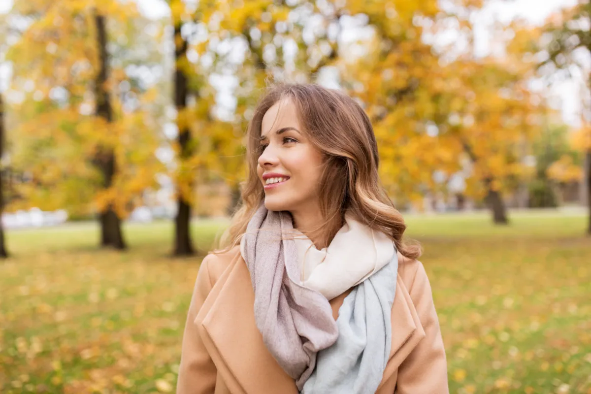 A girl in a scarf in an autumn park looks into the distance | Skylum Blog