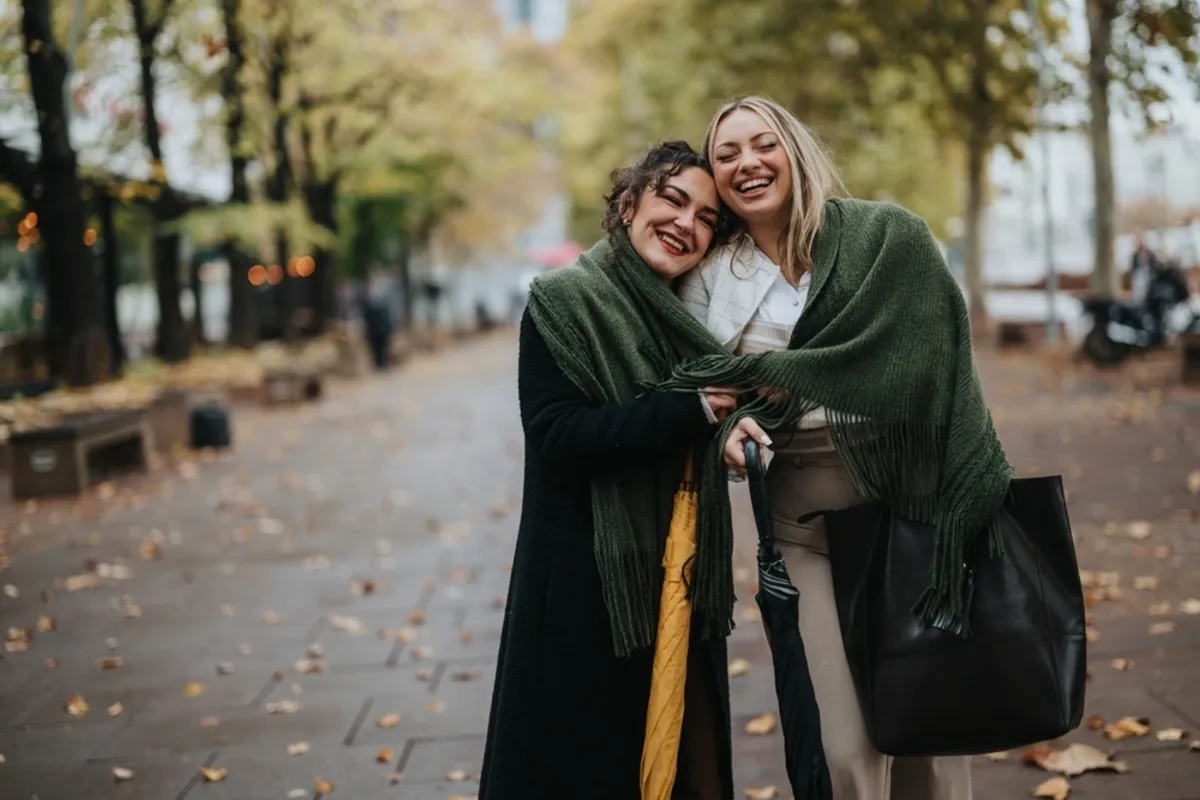 Two girls wrapped in a scarf in autumn | Skylum Blog