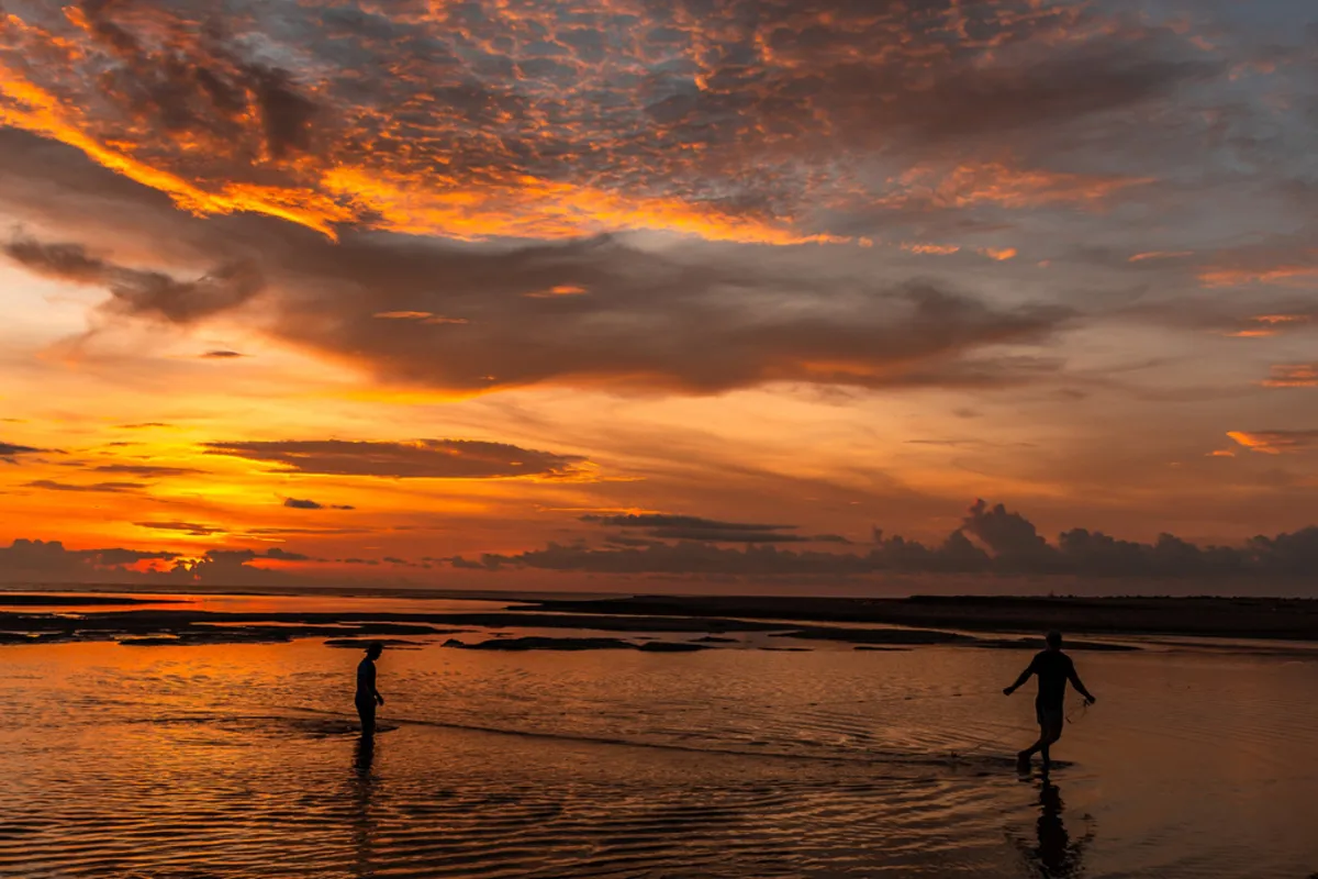 People in the water at sunset | Skylum Blog