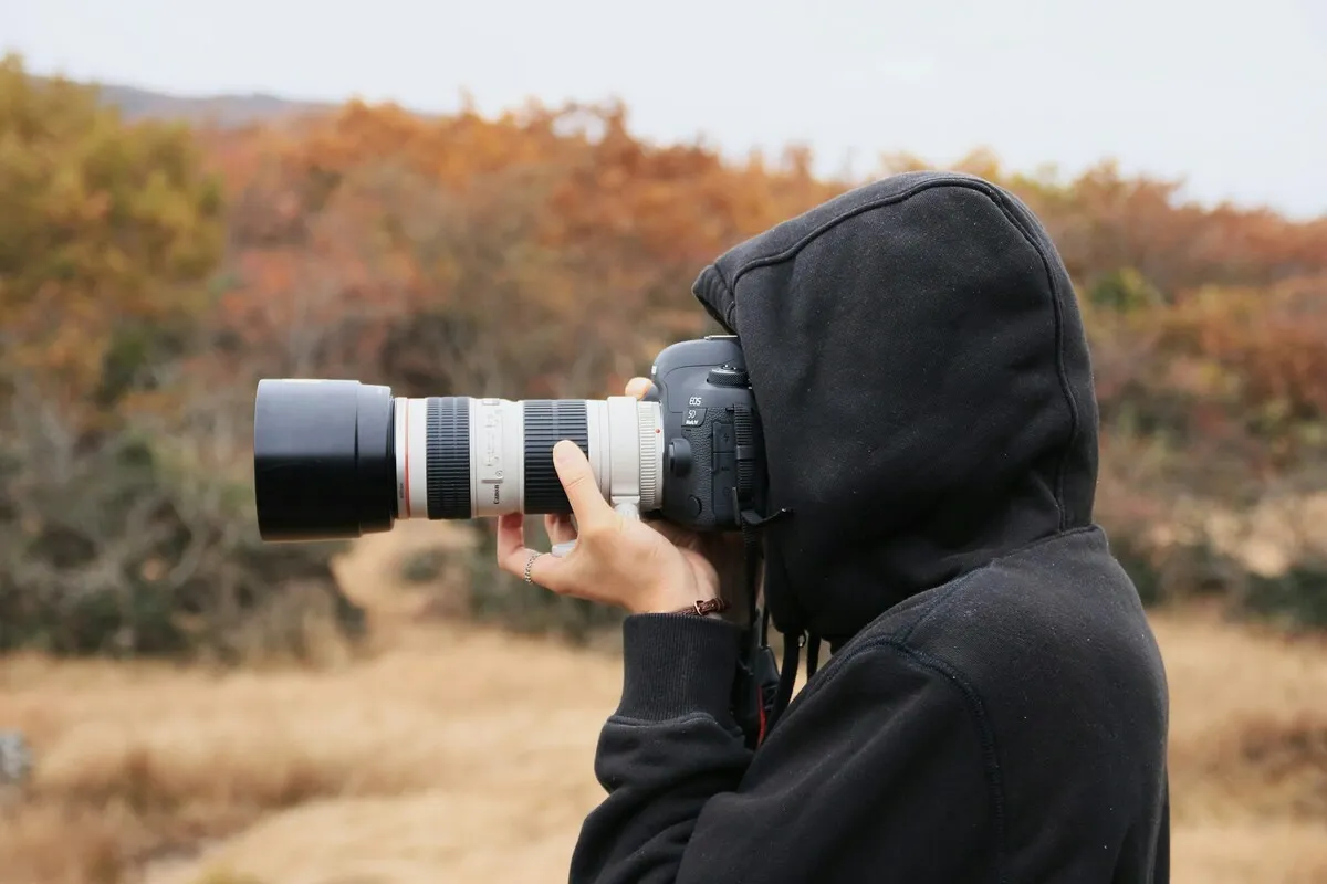 A photographer shoots with a camera using a telephoto lens | Skylum Blog
