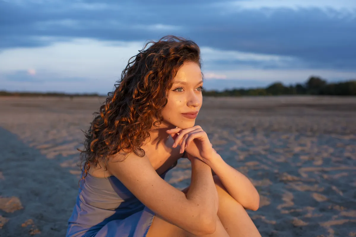 Portrait of a girl on the sand in front of the golden sun | Skylum Blog