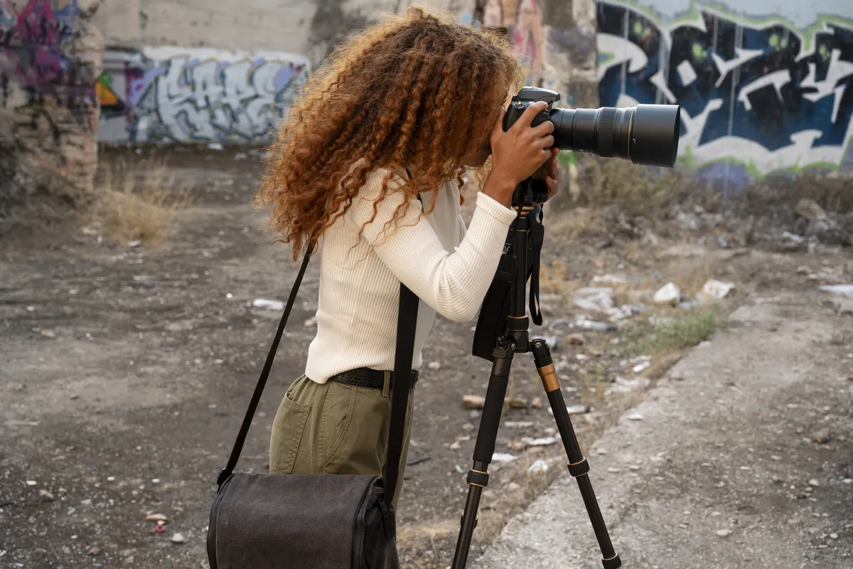 Photographer with a camera with a telephoto lens on a tripod | Skylum Blog