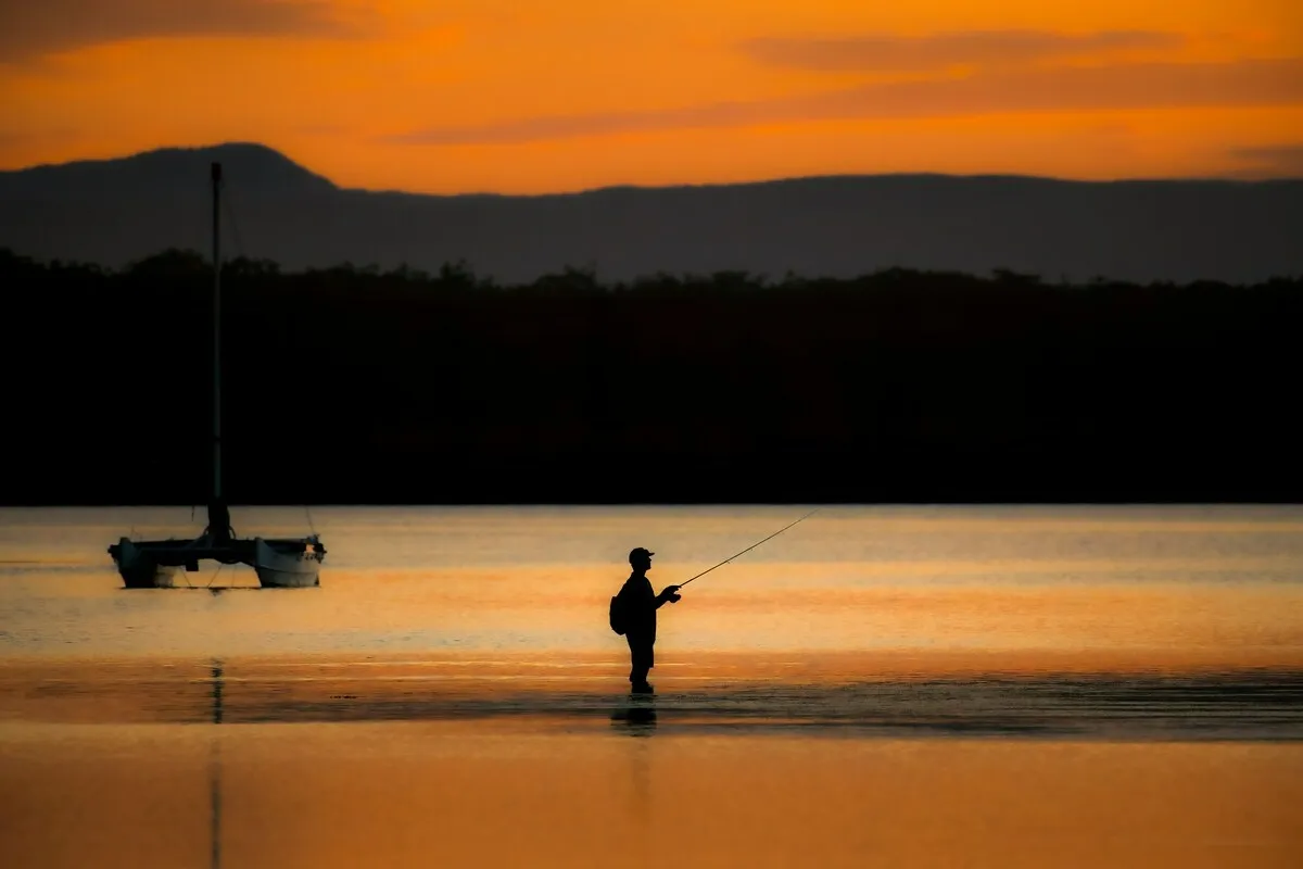 A photo of a fisherman in the water during golden hour | Skylum Blog