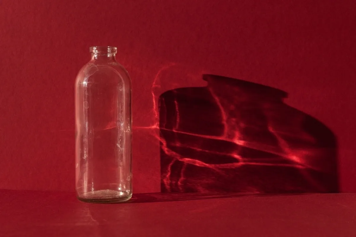 Glass bottle on a red background with reflection | Skylum Blog