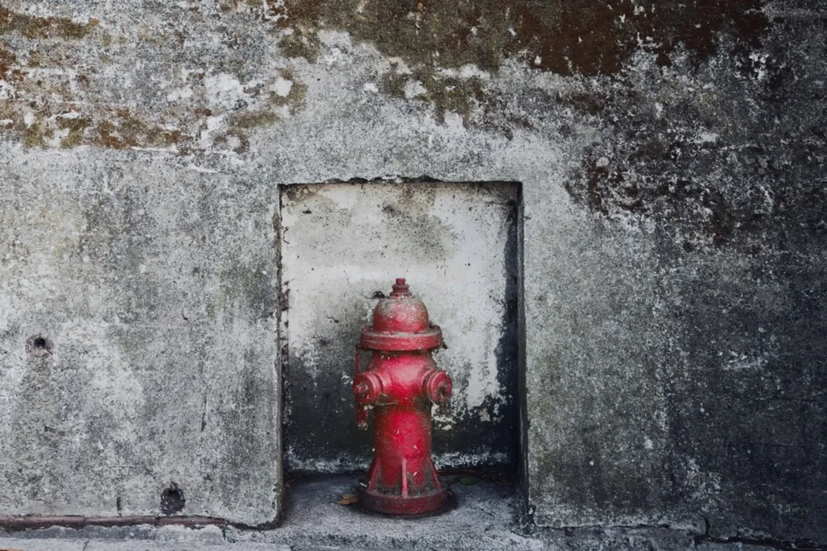 Abstract photo of a red hydrant against a gray wall | Skylum Blog