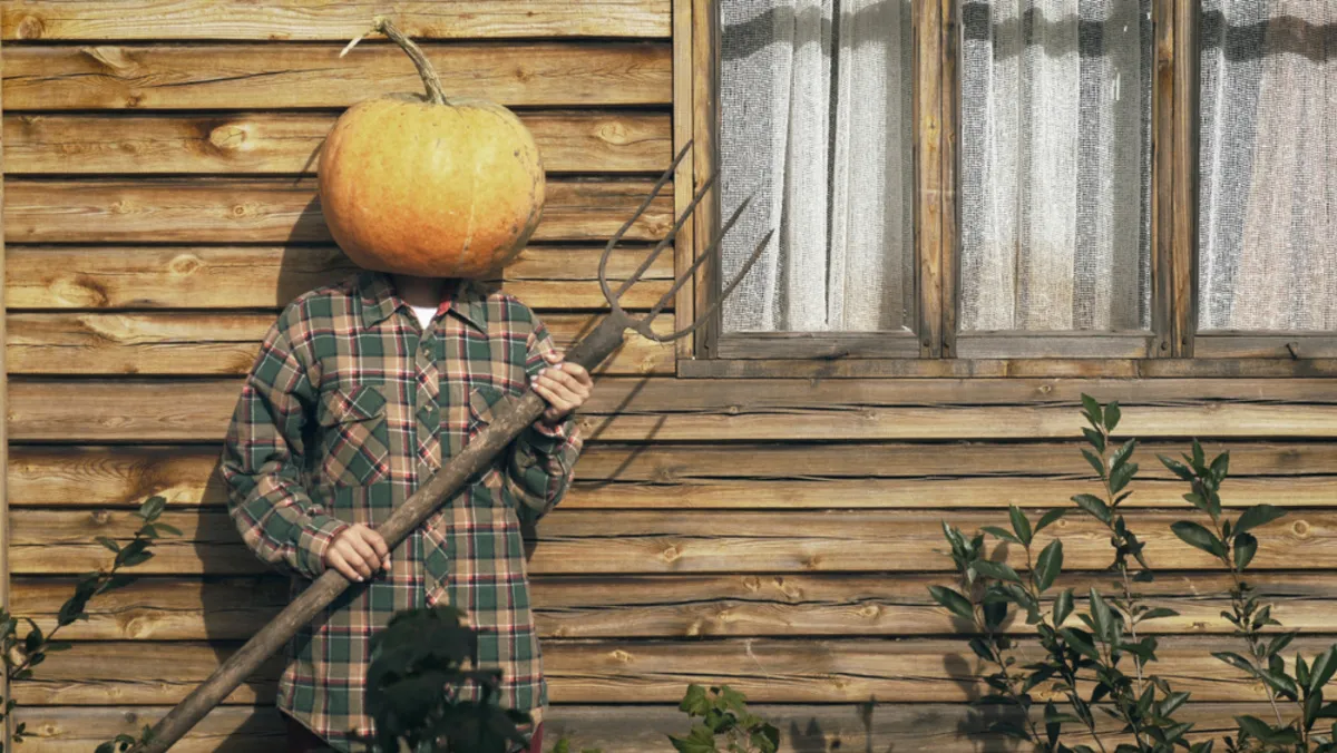 A man with a pumpkin on his head holds a pitchfork in his hands | Skylum Blog