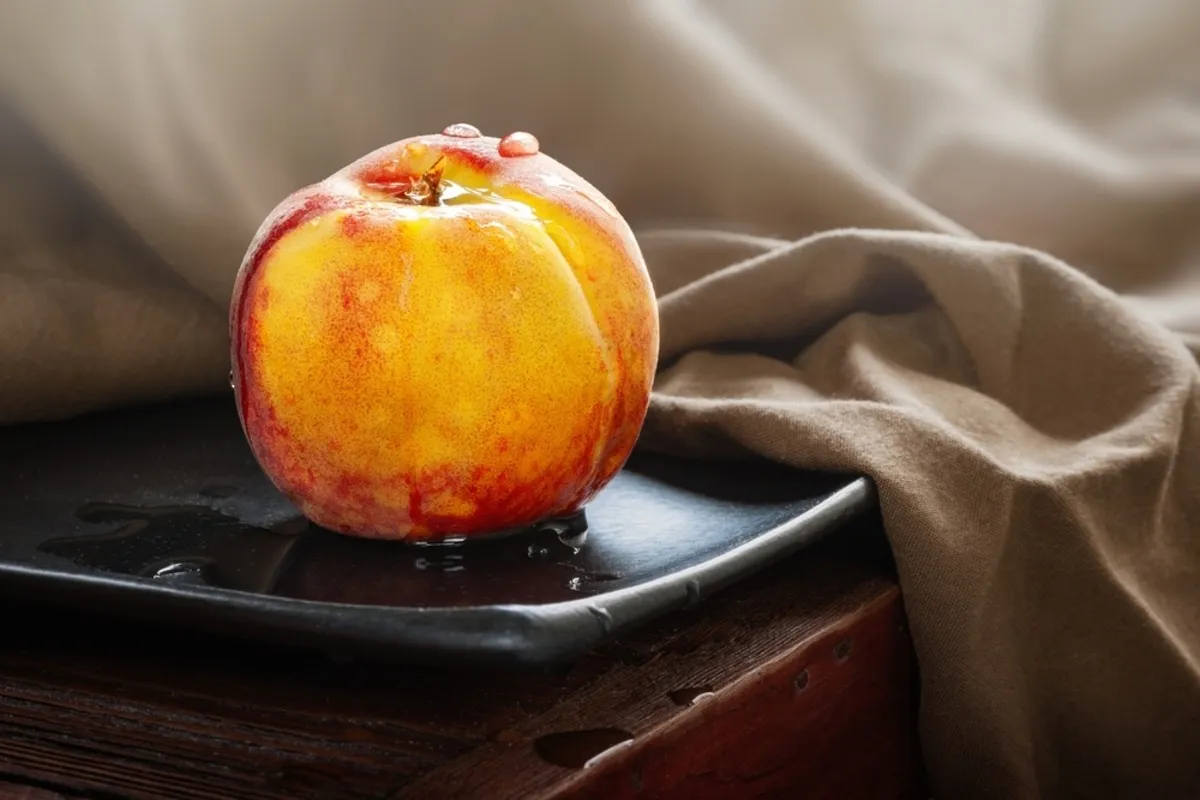 Photo of a peach on a black plate with fabric | Skylum Blog