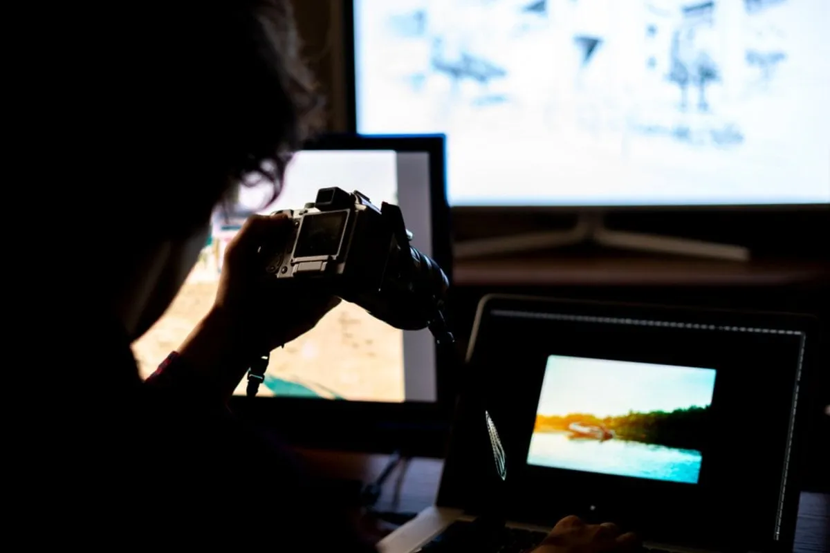 Photographer with a camera in front of laptops | Skylum Blog