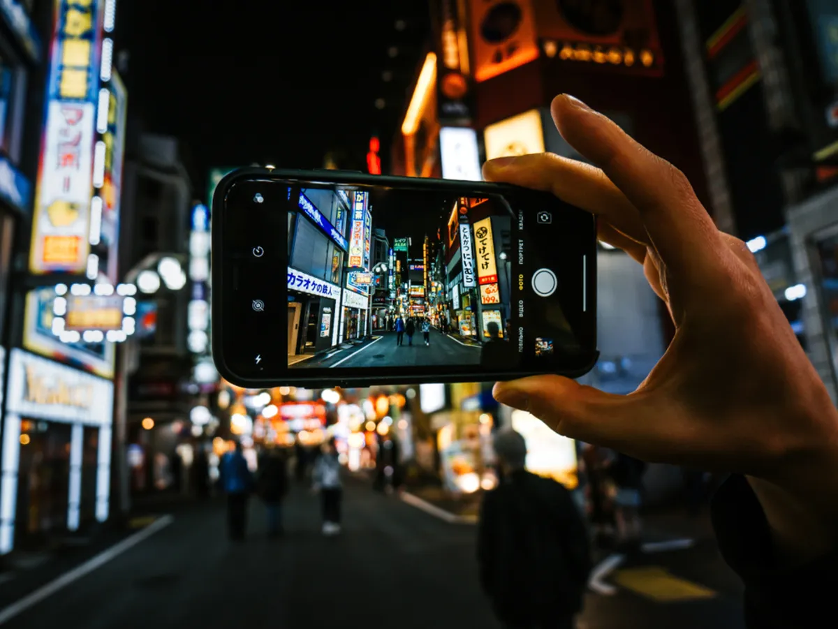 A man takes a photo of a city at night | Skylum Blog