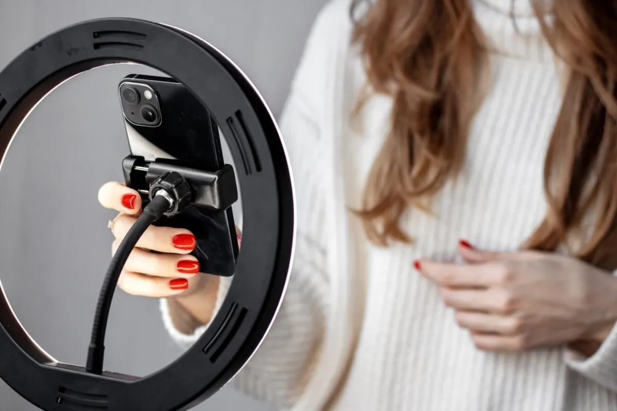 A girl adjusts an iPhone on a tripod | Skylum Blog