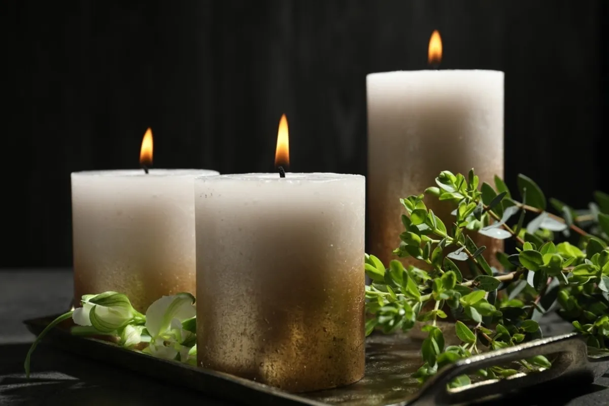 Lit golden candles on a tray with greenery | Skylum Blog