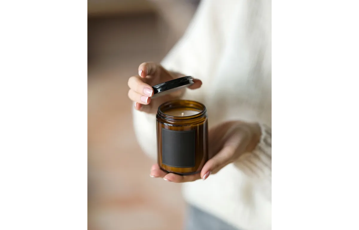 A candle in a glass jar in hands | Skylum Blog