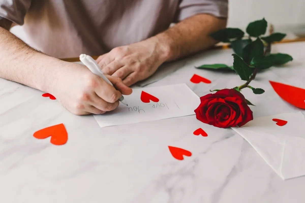 Hands cutting out paper hearts near a red rose | Skylum Blog