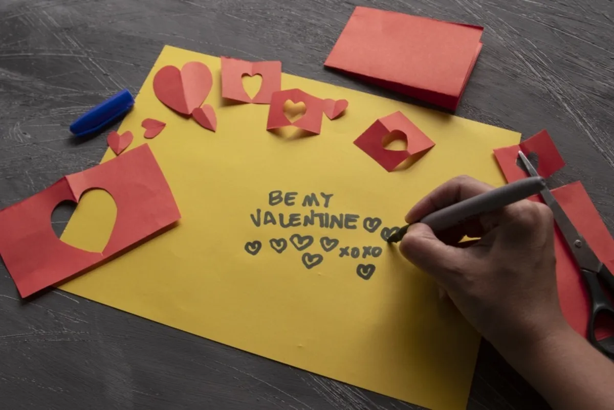 Hands writing a message on a yellow card with hearts | Skylum Blog