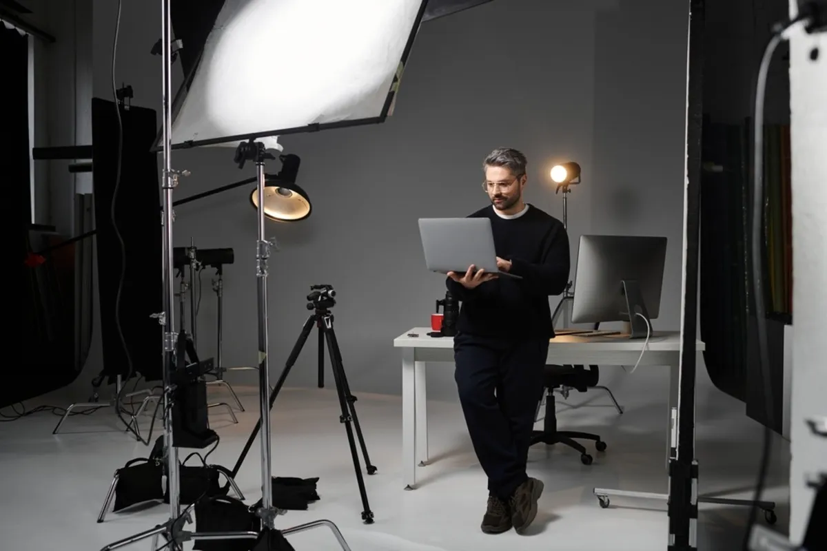 A photographer in a studio holding a laptop | Skylum Blog