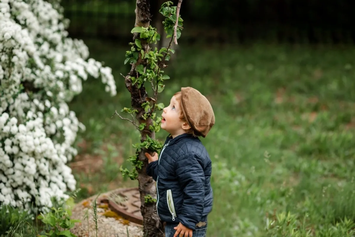 A surprised toddler looks at a spring tree | Skylum Blog
