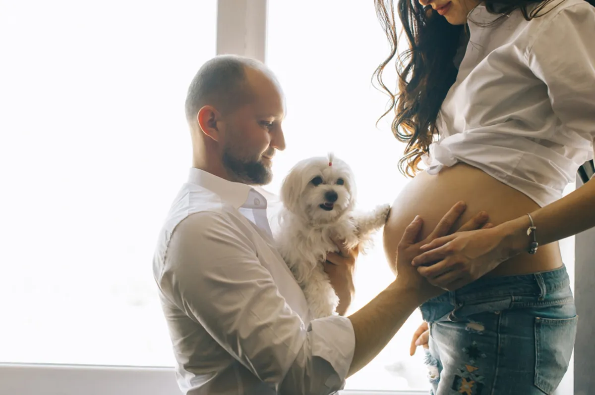 A man and his dog touch his wife's pregnant belly | Skylum Blog