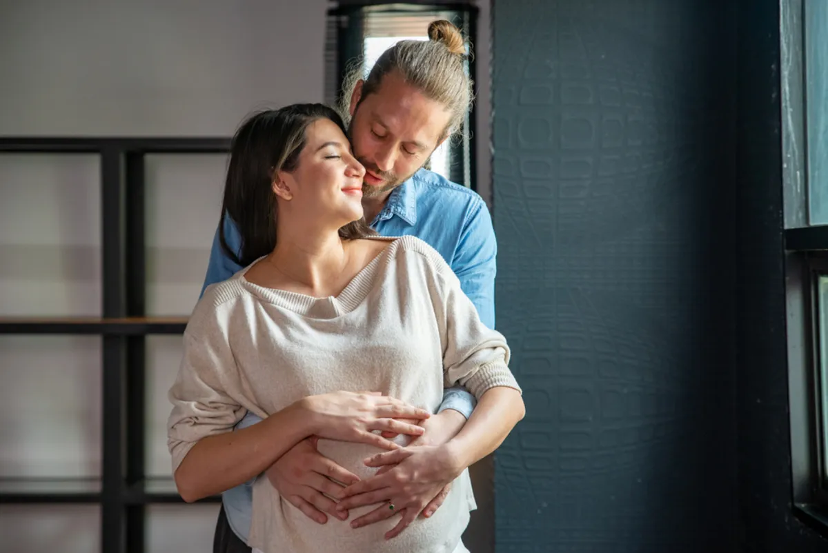 A man whispers into the ear of his pregnant wife | Skylum Blog
